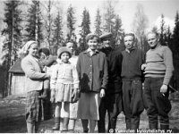 korpela(2)  Korpelan pihassa seisomassa vasemmalla Kerttu Ilmonen (o.s. Huusko, s. 24.6.1928) sylissään lapsi, oletettavasti Kertun ja Taiton tytär Pirkko  (s. 11.9.1957). Etualalla Korpelan kasvattityttö (onko Terttu Kytönen? vrt. kuva 2684), takanaan Korpelan emäntä Lempi Salonen (o.s. Kuparinen, 15.10.1914 - 24.1.2005) Toinen oikealta Kertun aviomies Taito Ilmonen (10.4.1924 - 11.8.2005) ja äärimmäisenä oikealla Lempin aviomies (Kertun serkku) Timo Salonen (25.5.1911 - 3.8.1993). Kaksi muuta tunnistamattomia.