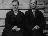 Pitk(42)  Anna (o.s. Lehtinen) ja Sulo Teräjuuri istuvat hirsiseinän vierellä